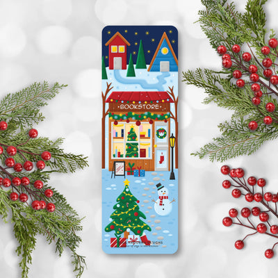 Christmas-themed bookmark with a snowy village scene, surrounded by festive decorations on a light gray background.