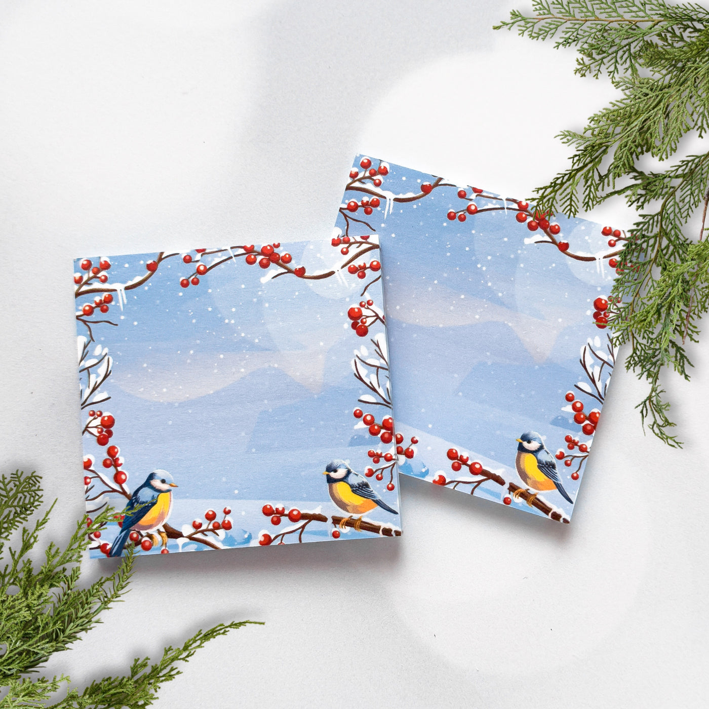 Two folded cards with winter scene design featuring birds and berries on a white background.