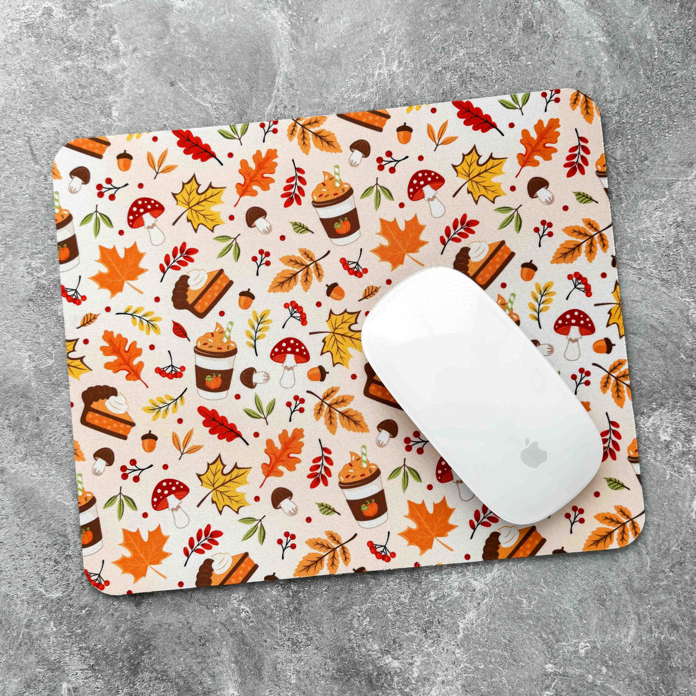 Mouse pad with autumn-themed design featuring leaves, pumpkins, and other fall elements on a gray surface.