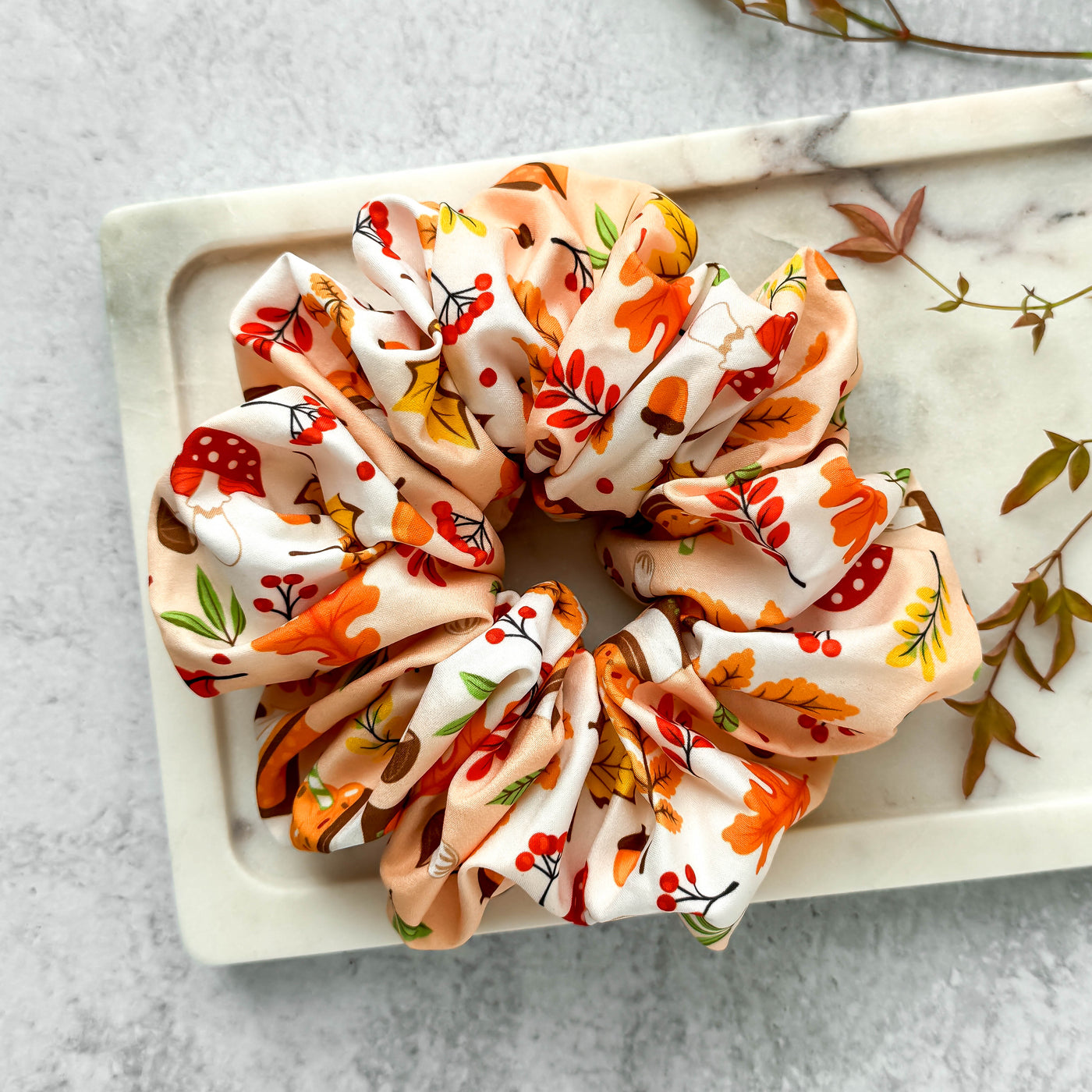 Autumn-themed scrunchie on a marble tray with a light background.