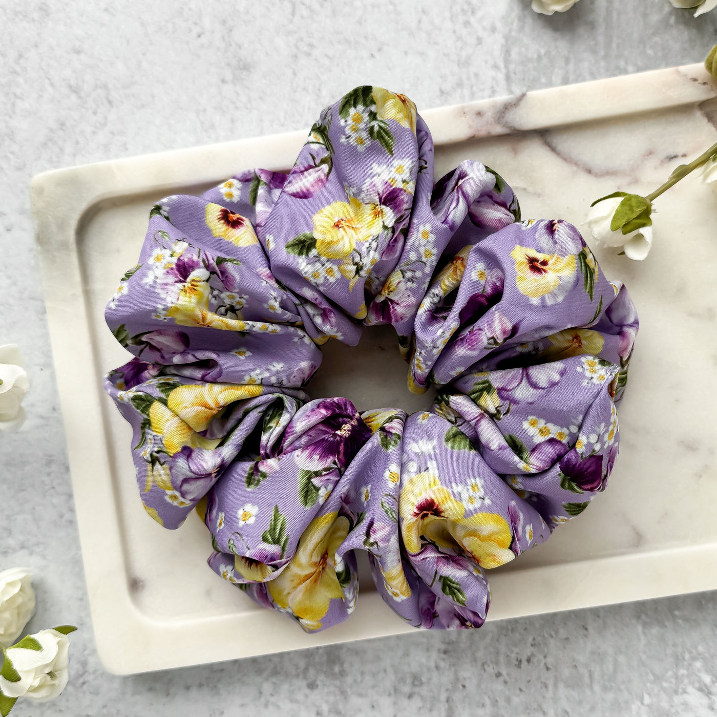 Floral scrunchie on a marble tray with flowers around.