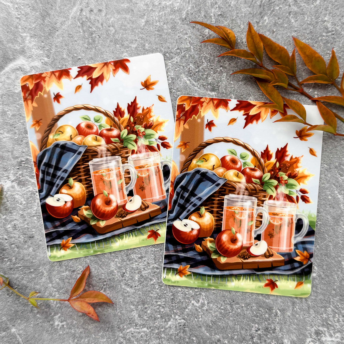 Two autumn-themed cards with apples, mugs, and a basket on a gray surface.