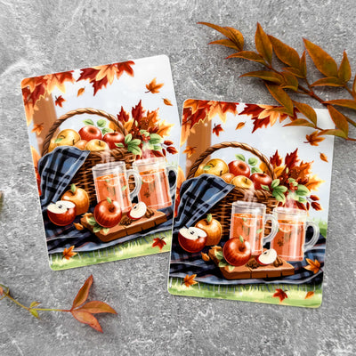 Two autumn-themed cards with apples, mugs, and a basket on a gray surface.