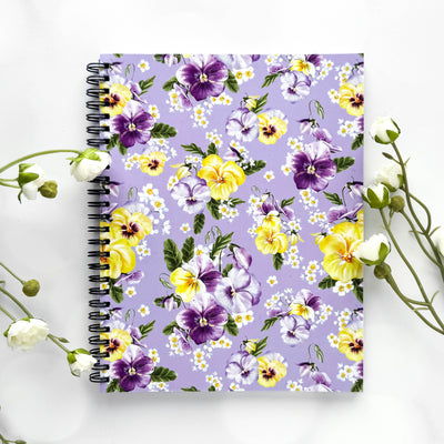 Floral notebook with purple, yellow, and white flowers on a light purple background.