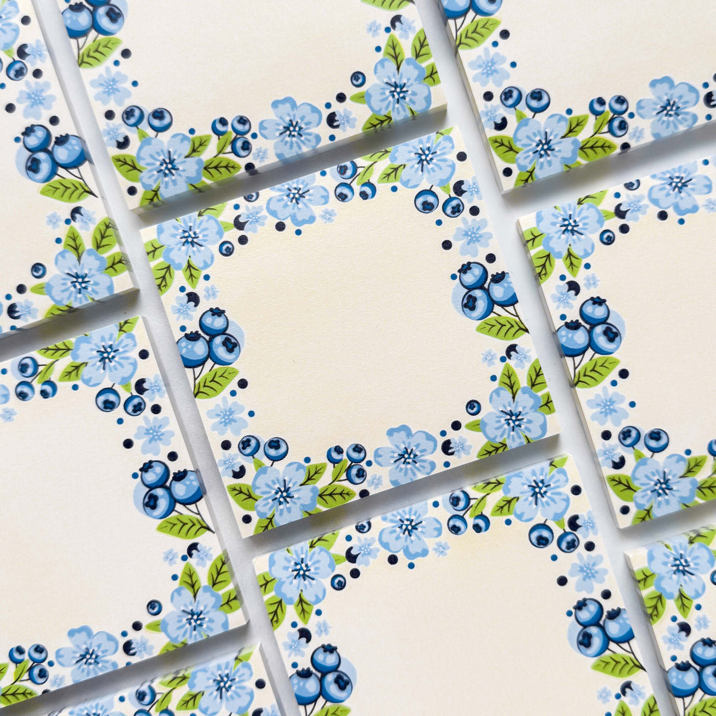 Sticky memo pads with blue floral pattern on a beige background.