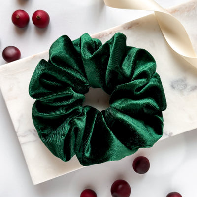 Green scrunchie on a marble surface with dark berries.