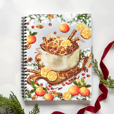 Notebook with a festive design featuring a pot of spiced fruit on a white background.