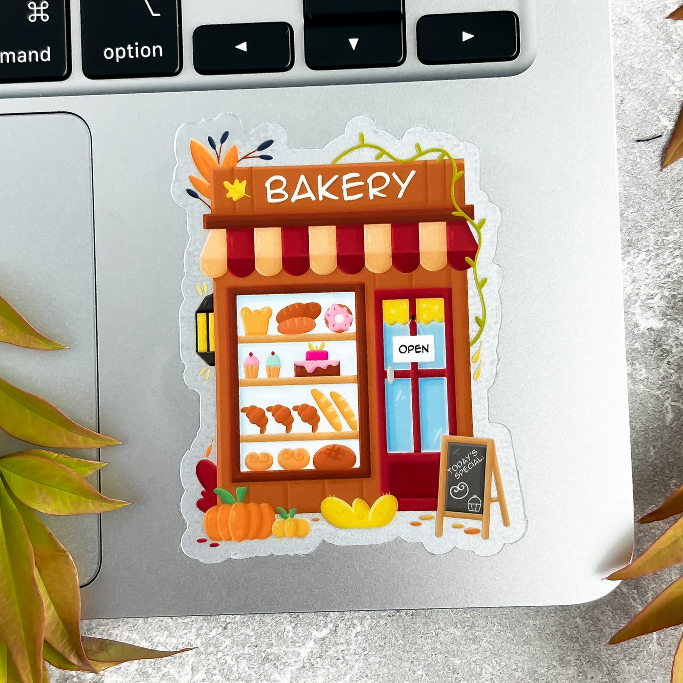 Cartoon bakery sticker on a laptop keyboard with decorative elements.