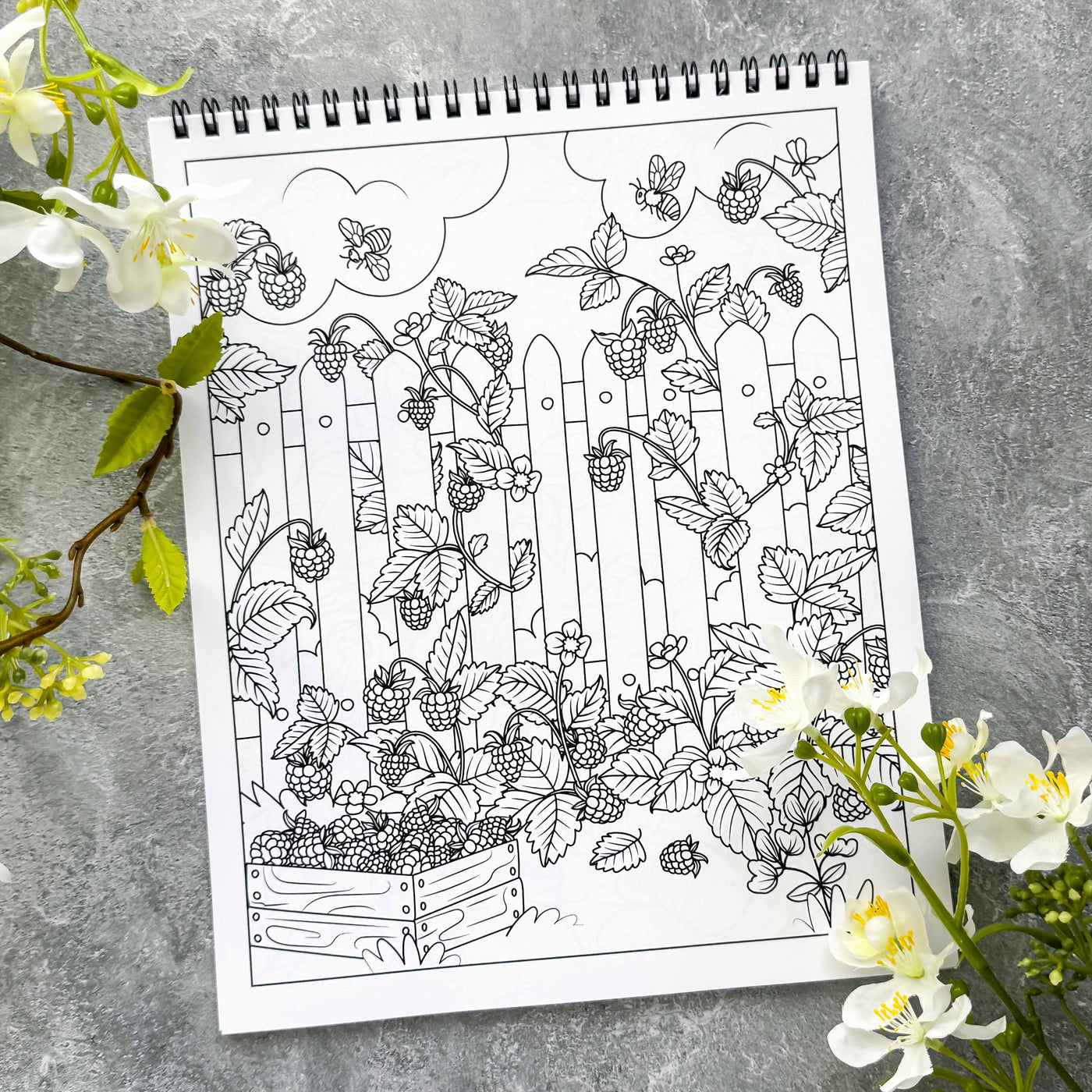Coloring book page with garden design on a gray surface with flowers.
