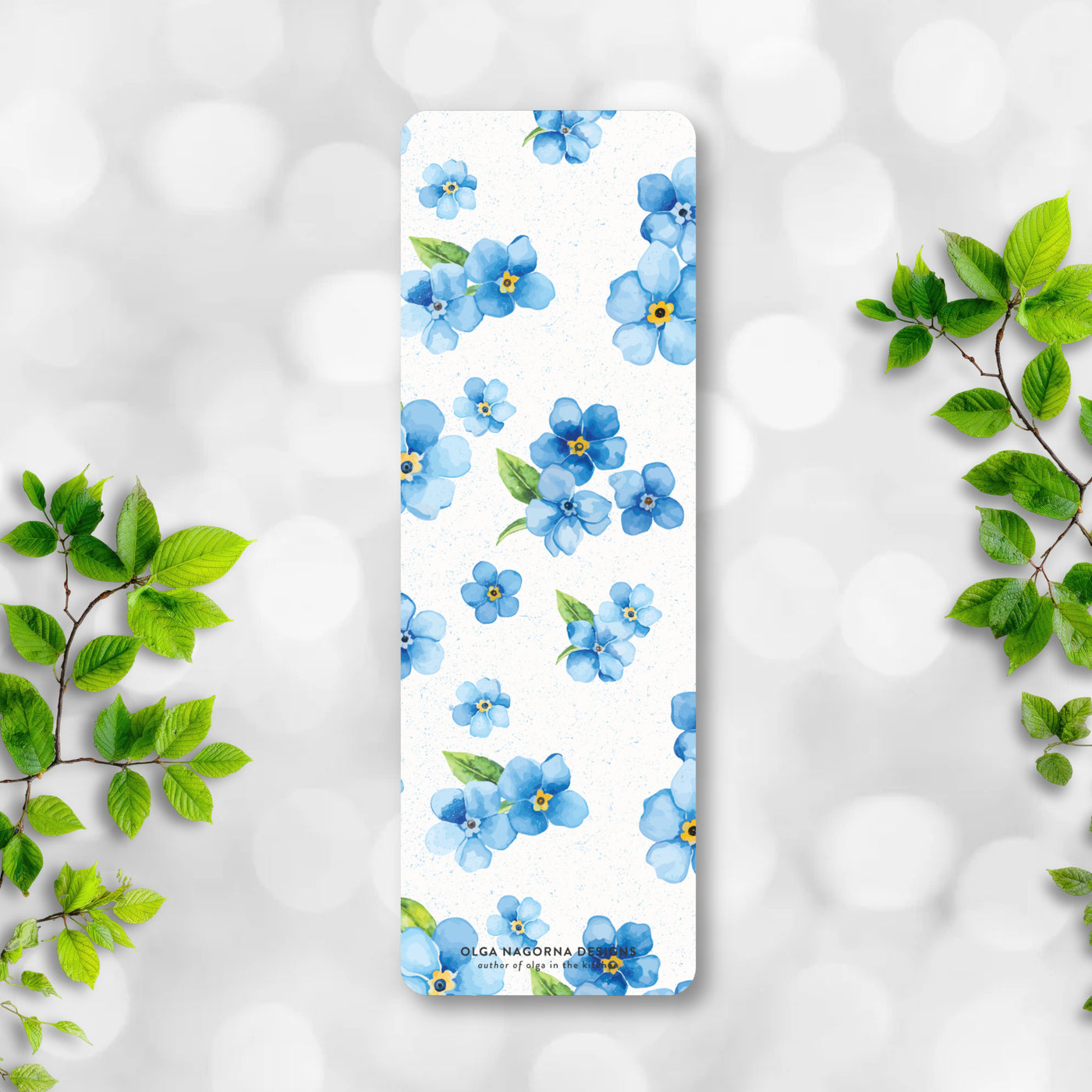 Bookmark with blue floral design on a white background with green leaves.
