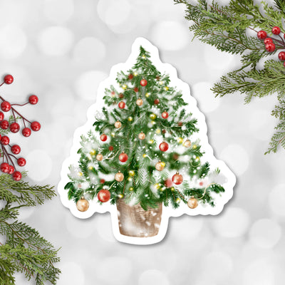 Decorative sticker of a Christmas tree with ornaments on a snowy background.