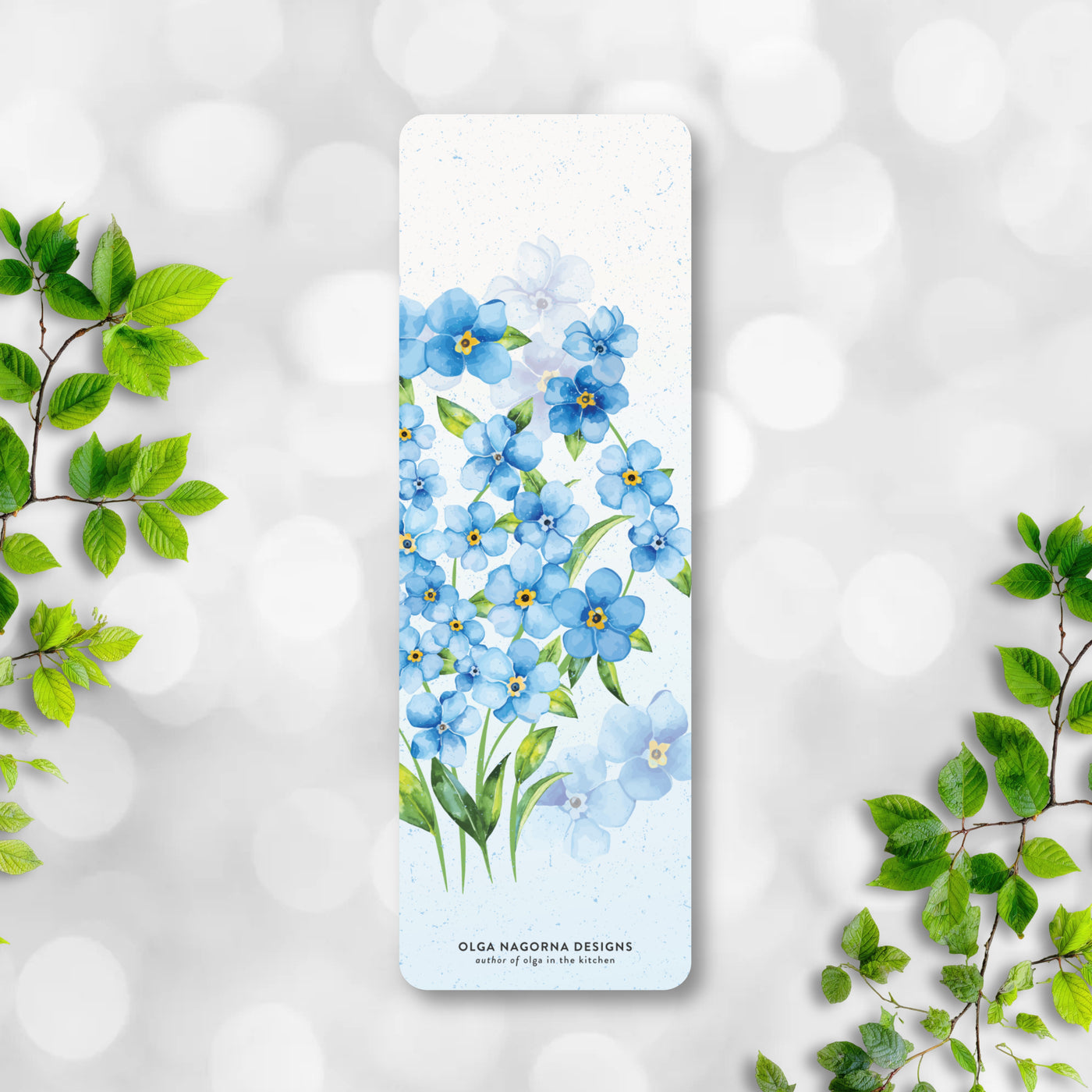 Bookmark with blue floral design on a white background with green leaves.