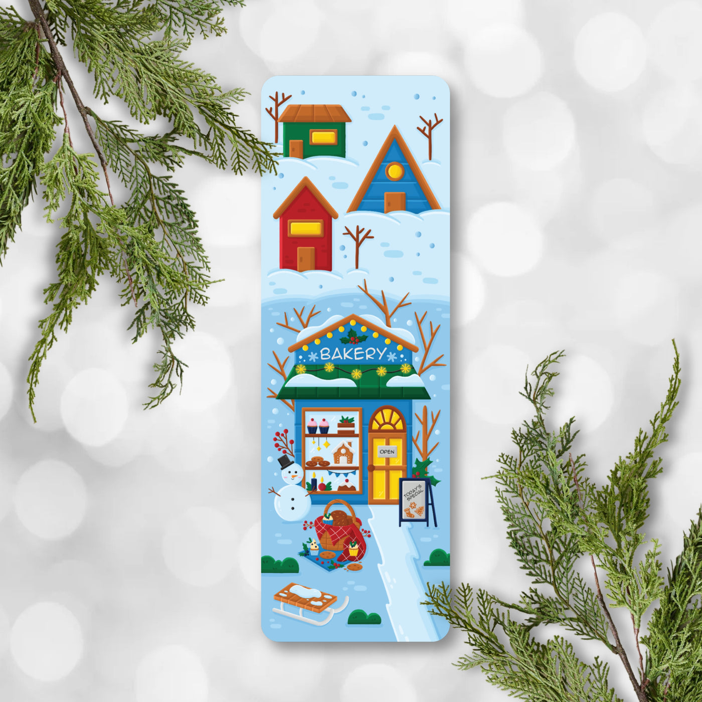 Colorful winter-themed bookmark with houses and a bakery on a snowy background.
